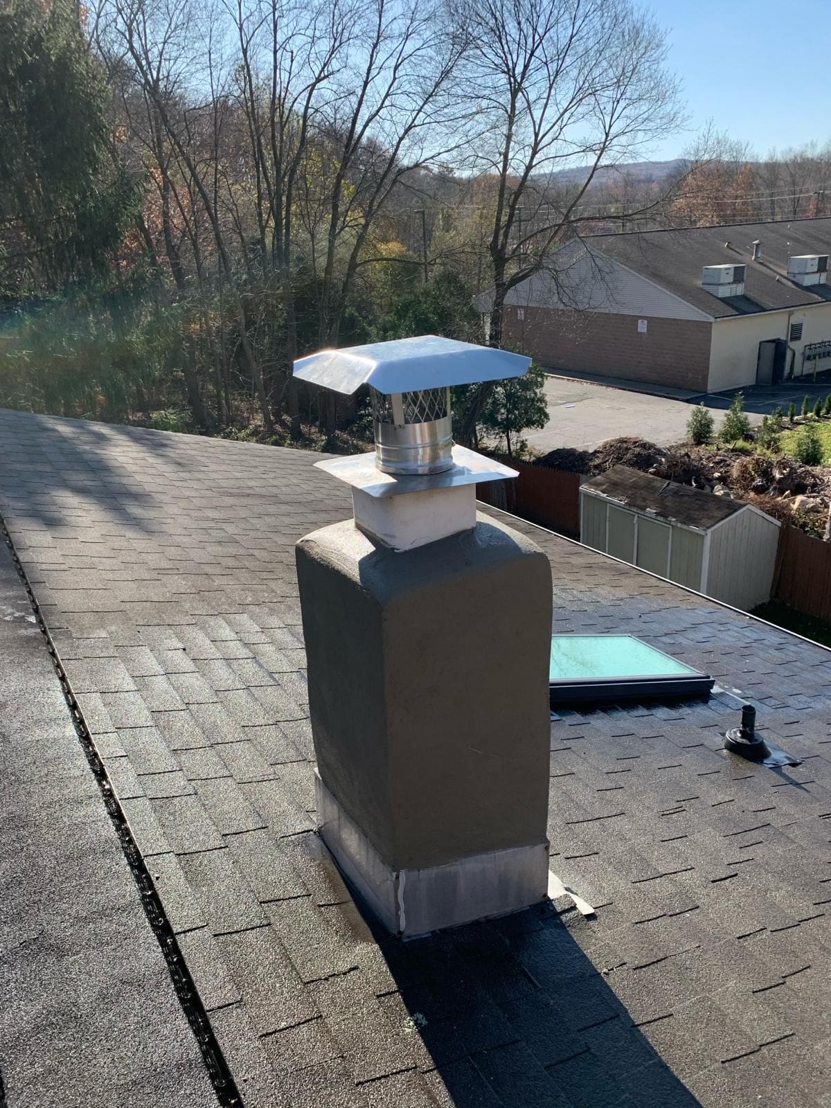 Chimney chase with a new cap on a shingle roof
