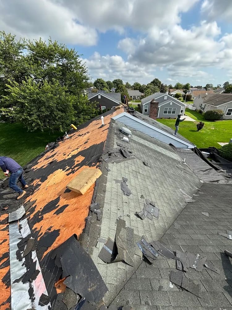 Worn and damaged shingles being torn off a roof