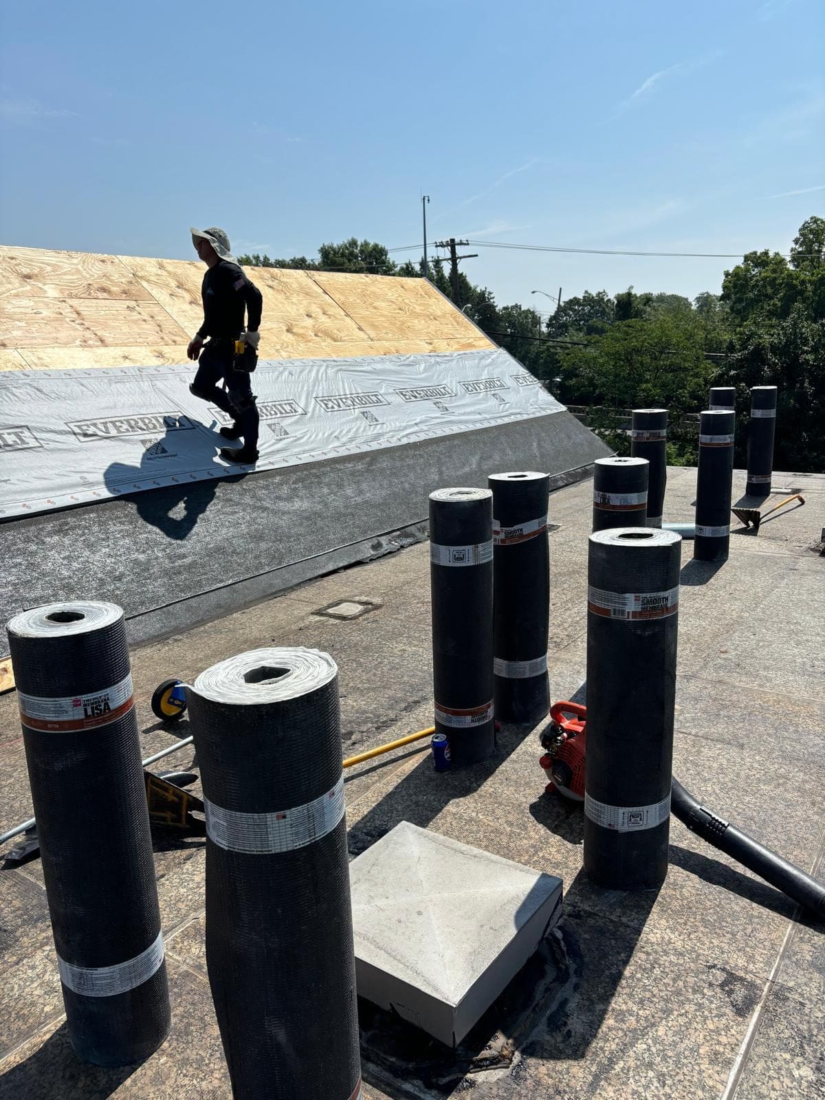 Modified bitumen rolls staged on a flat roof before installation