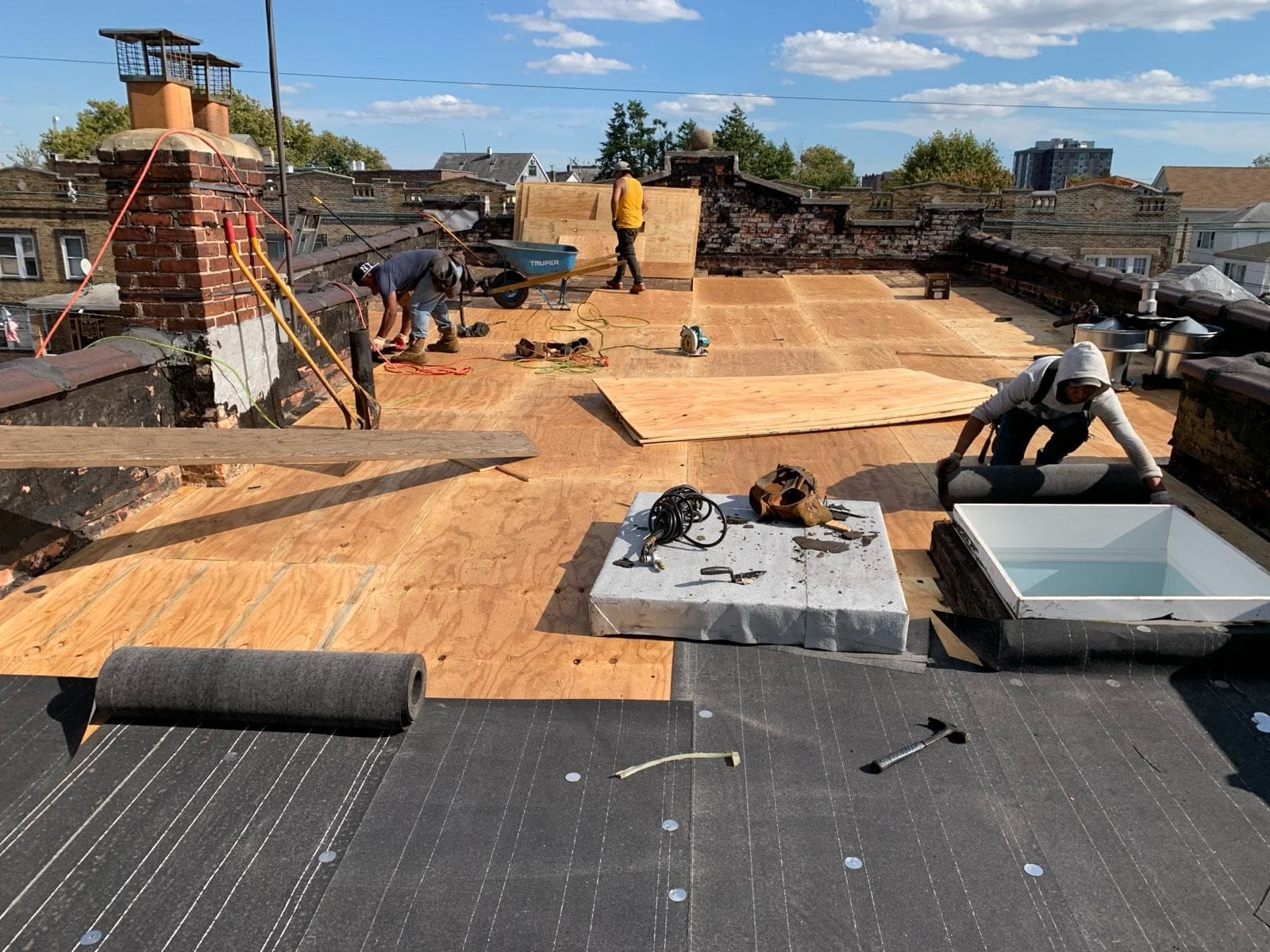 Flat roof replacement around a skylight and brick chimneys