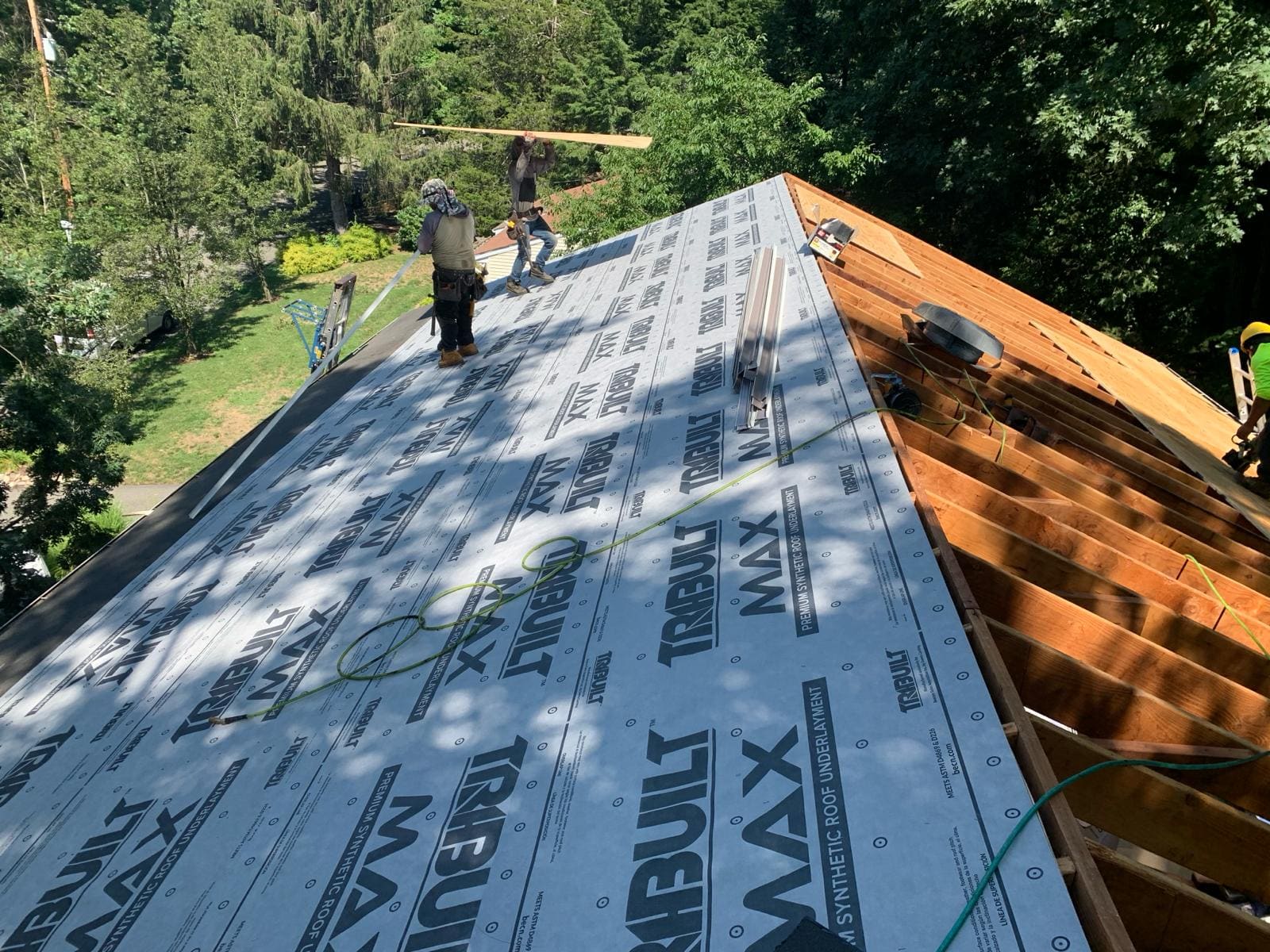 Roof replacement in progress: new plywood decking and synthetic underlayment being installed