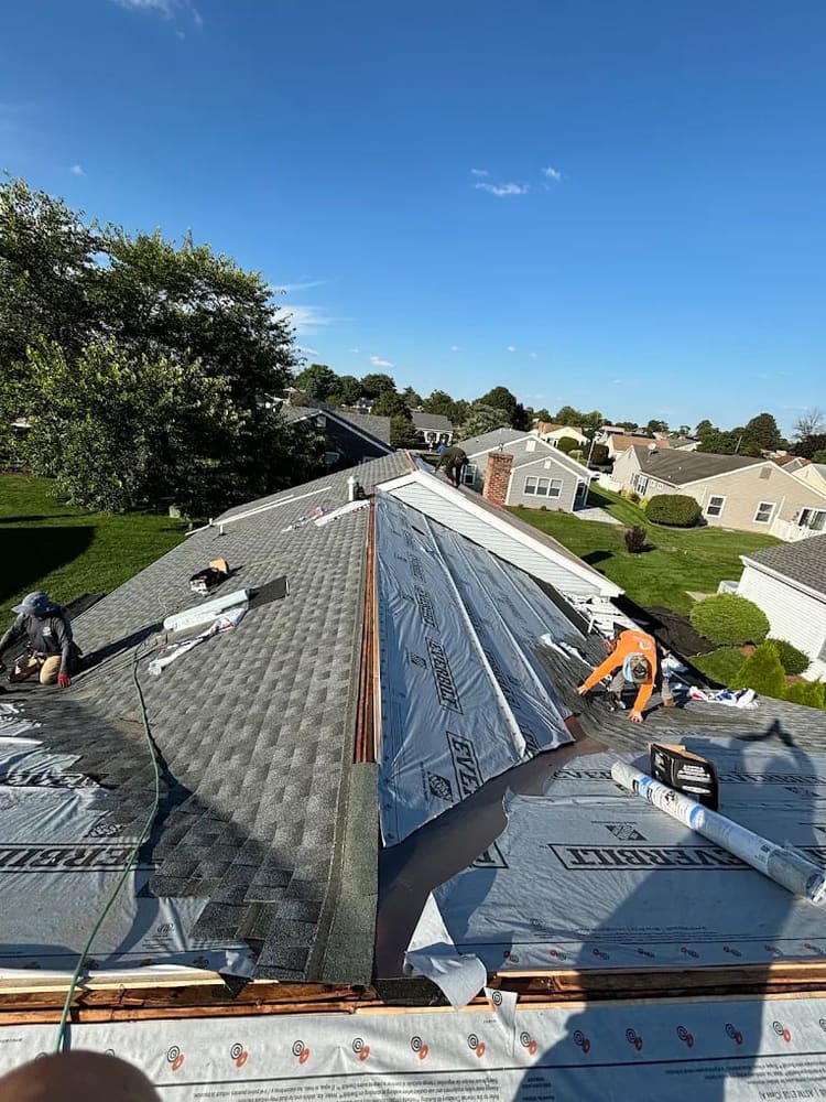 Ridge cap shingles being installed along the peak of a new roof