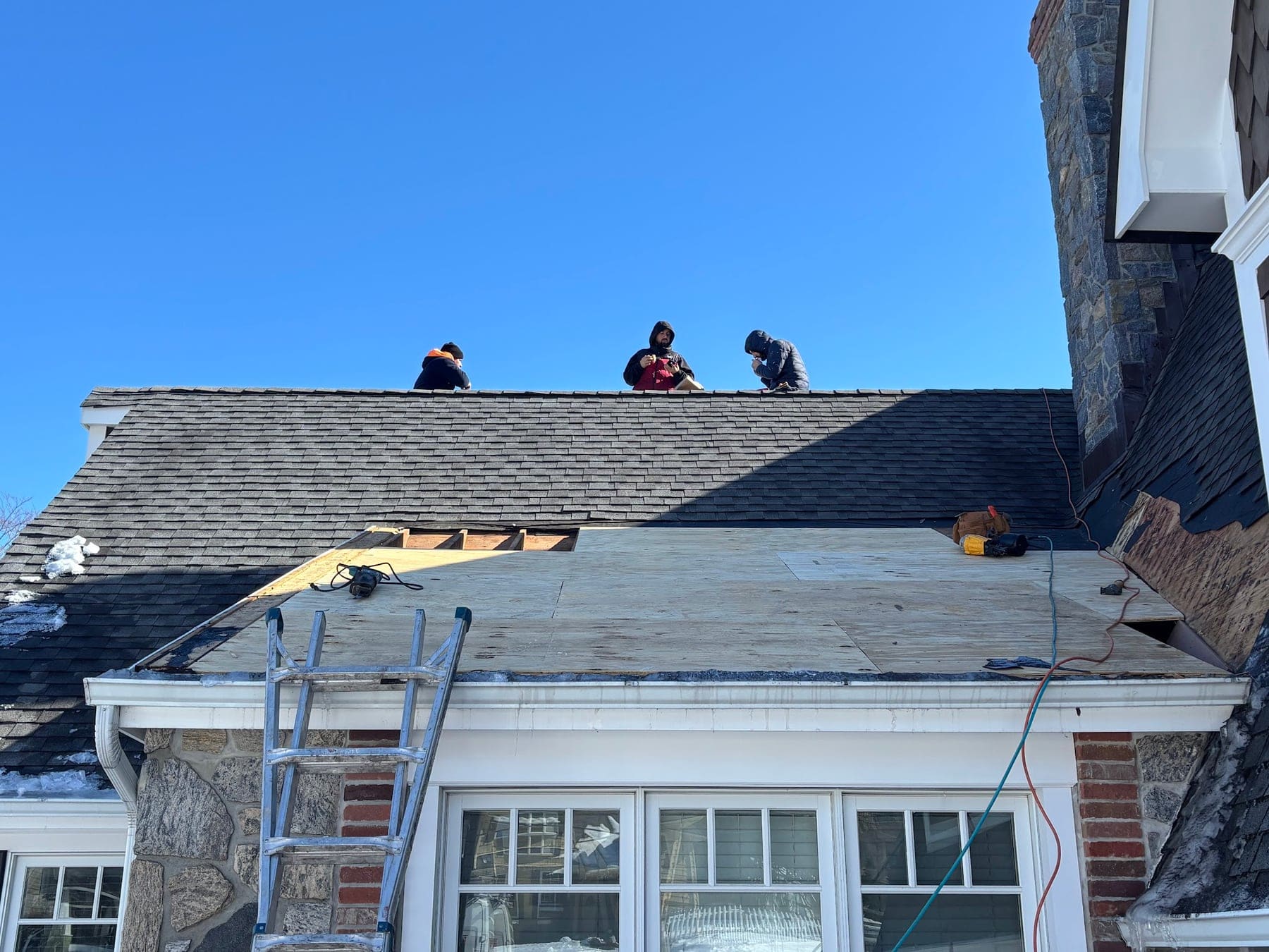 Crew replacing the roof on a brick colonial home