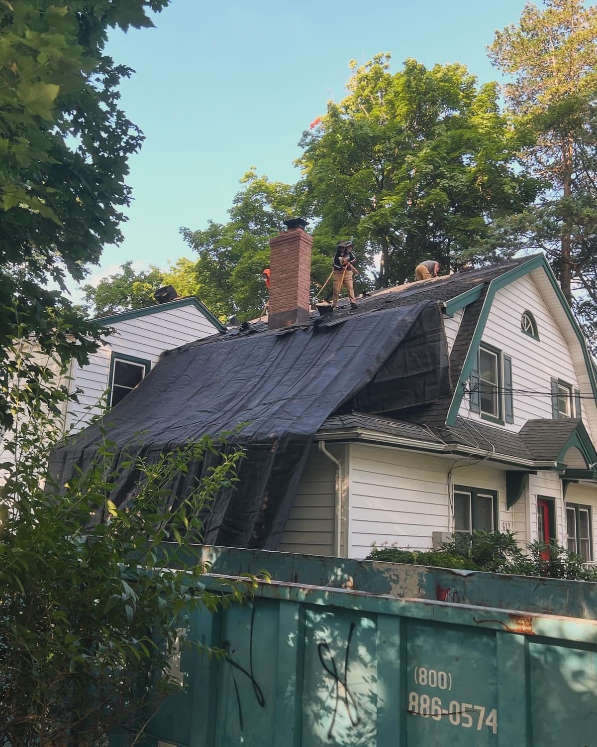 Home wrapped in tarps to protect siding during a roof replacement