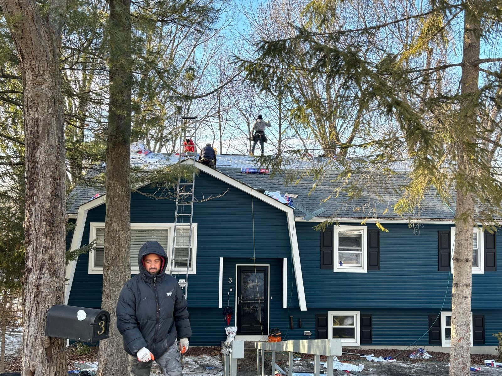 Winter roof replacement on a blue split-level home